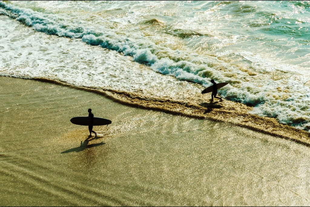 Surfers komen uit het water op het strand van Biarritz.